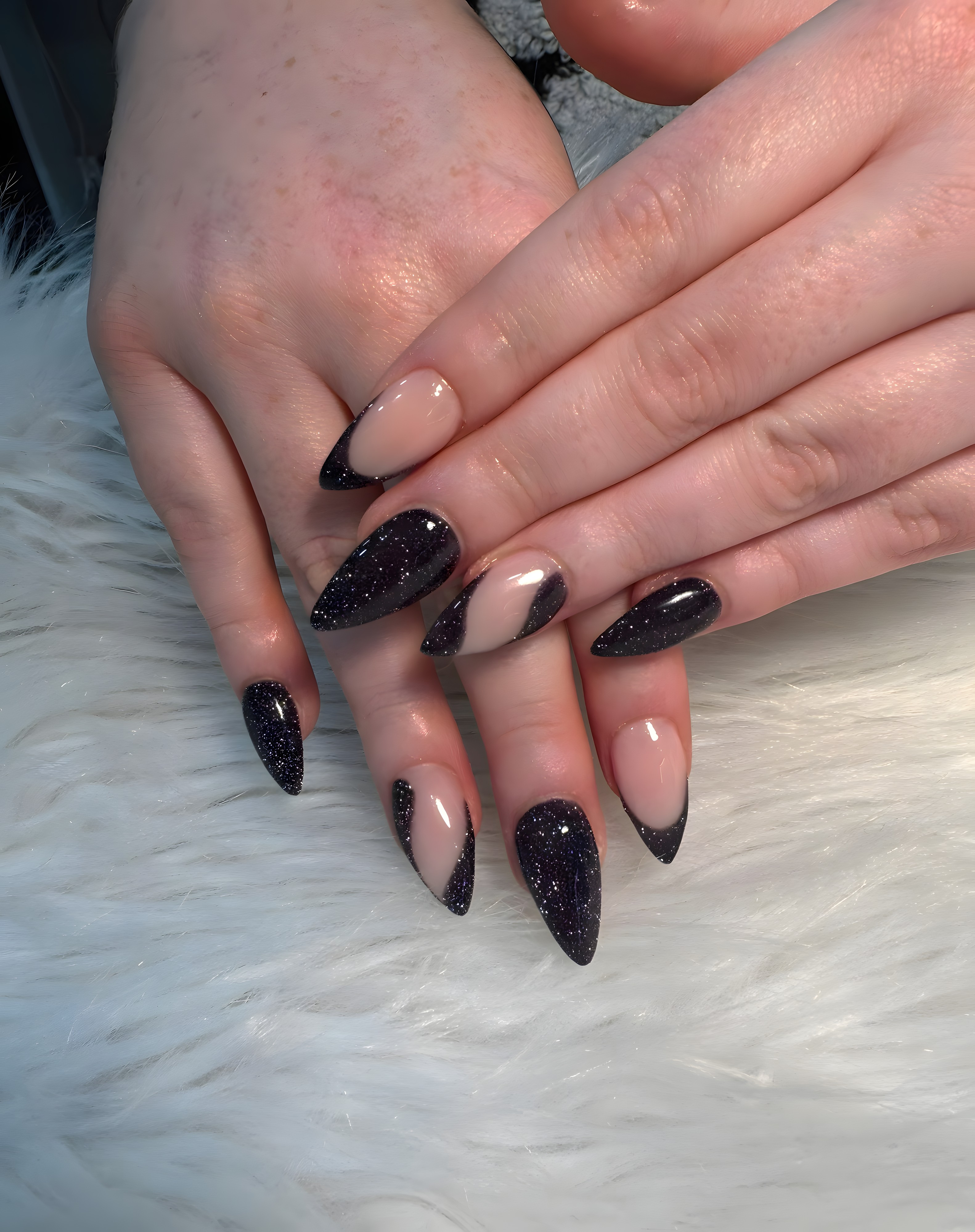 Black glitter stiletto nails with a nude negative-space design, done at LoveLe